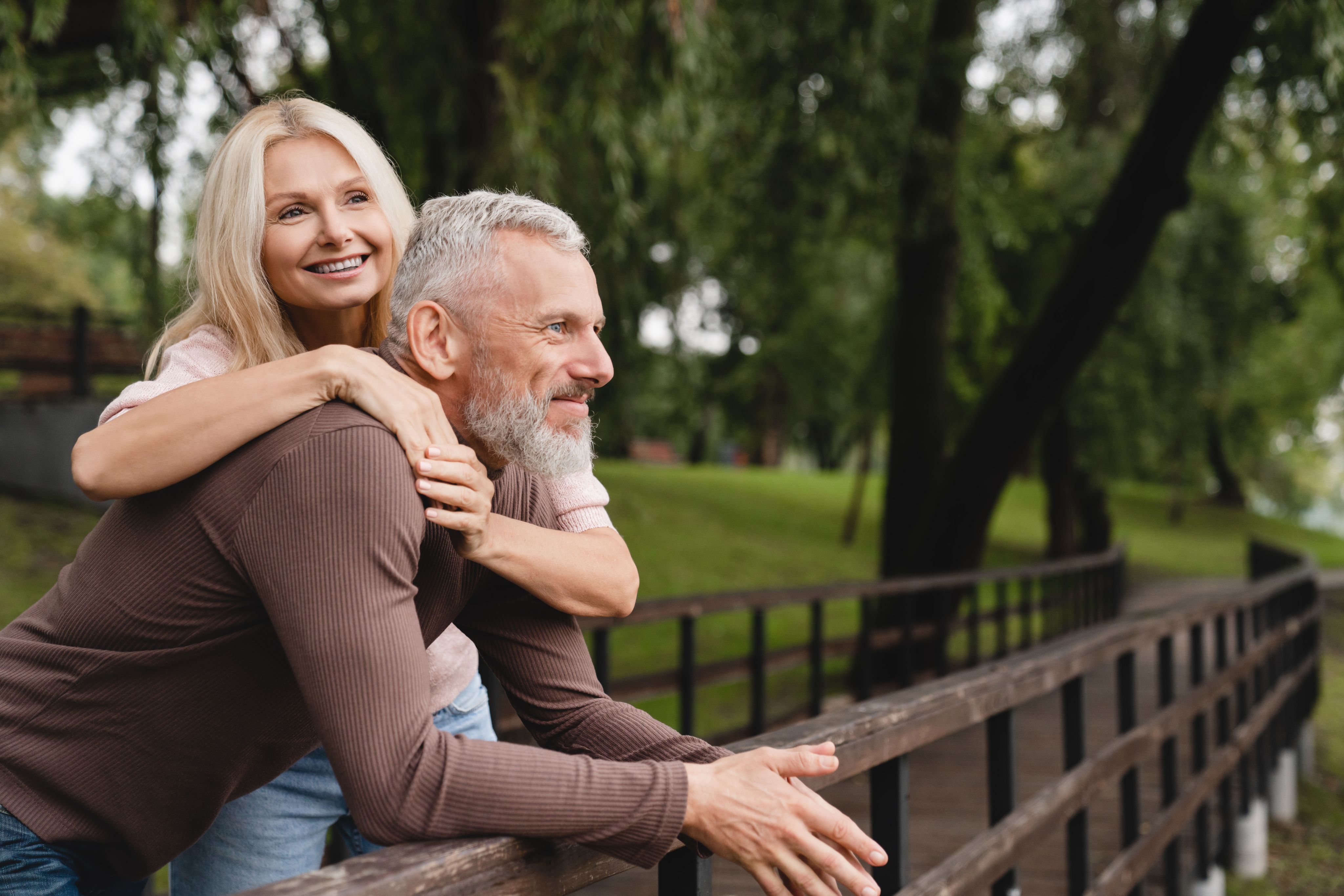 Couple in their 50s smiling together outdoors, illustrating the feel-better-again goal of peptide therapy.