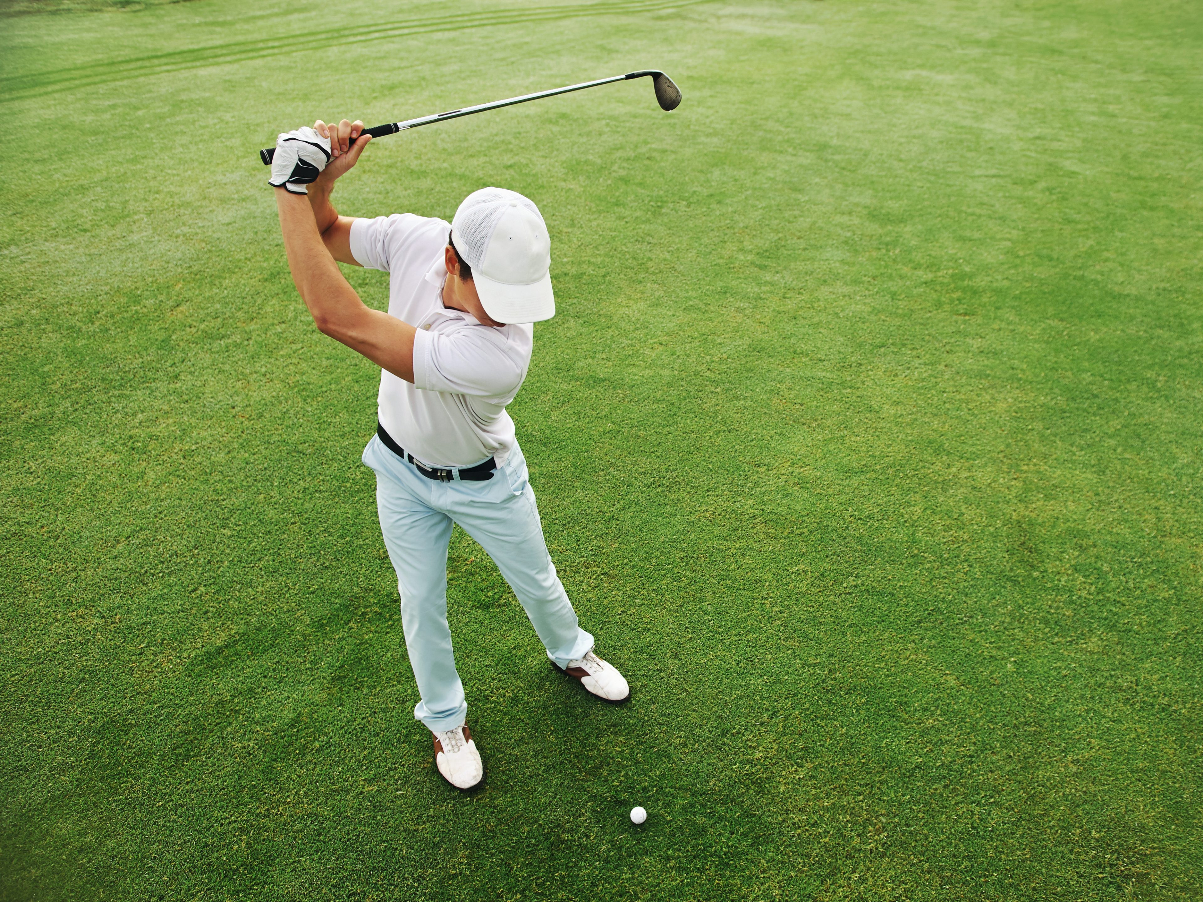 Man mid-swing on a sunlit golf course, showing the vitality peptide therapy supports.