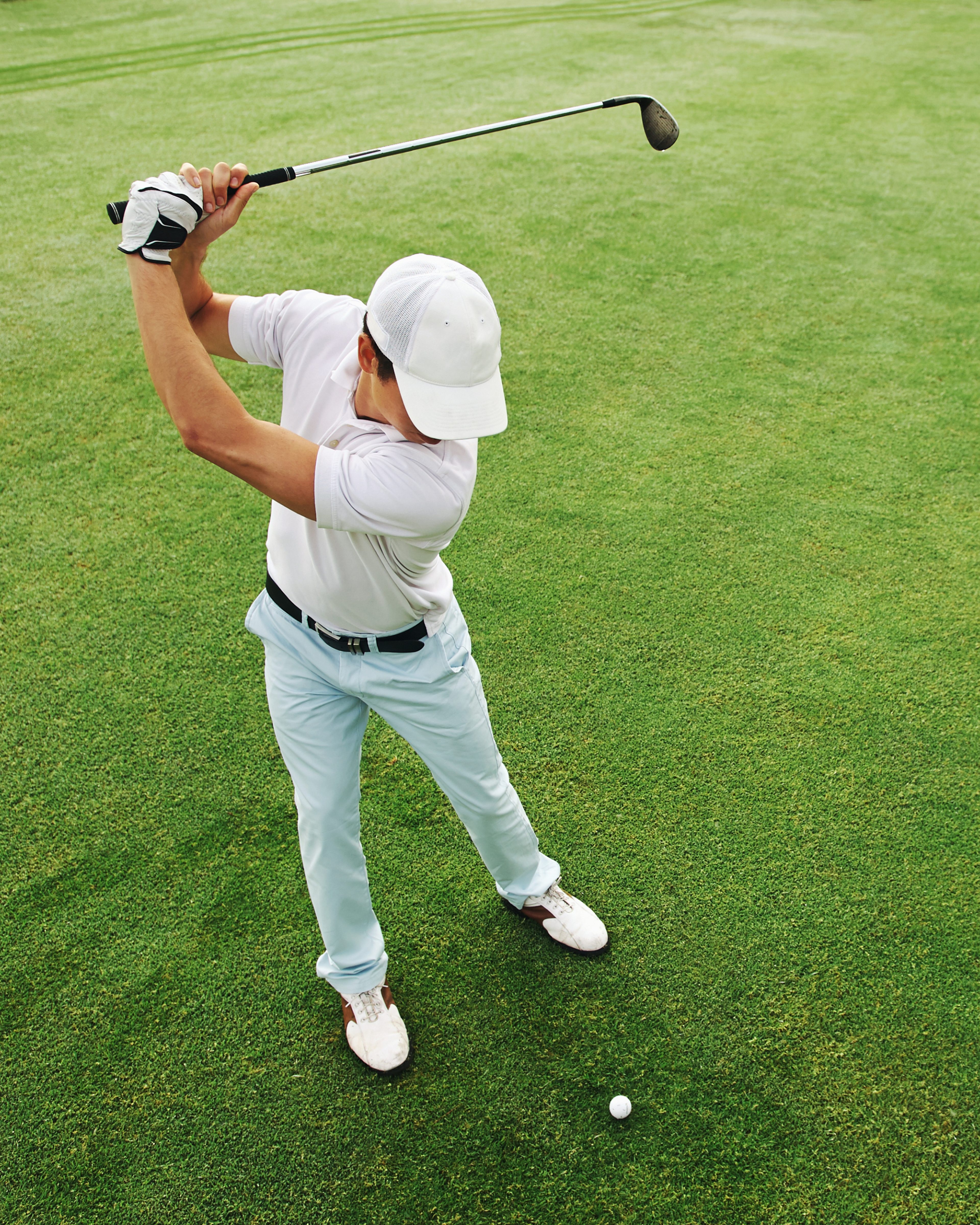 Man mid-swing on a sunlit golf course, showing the vitality peptide therapy supports.