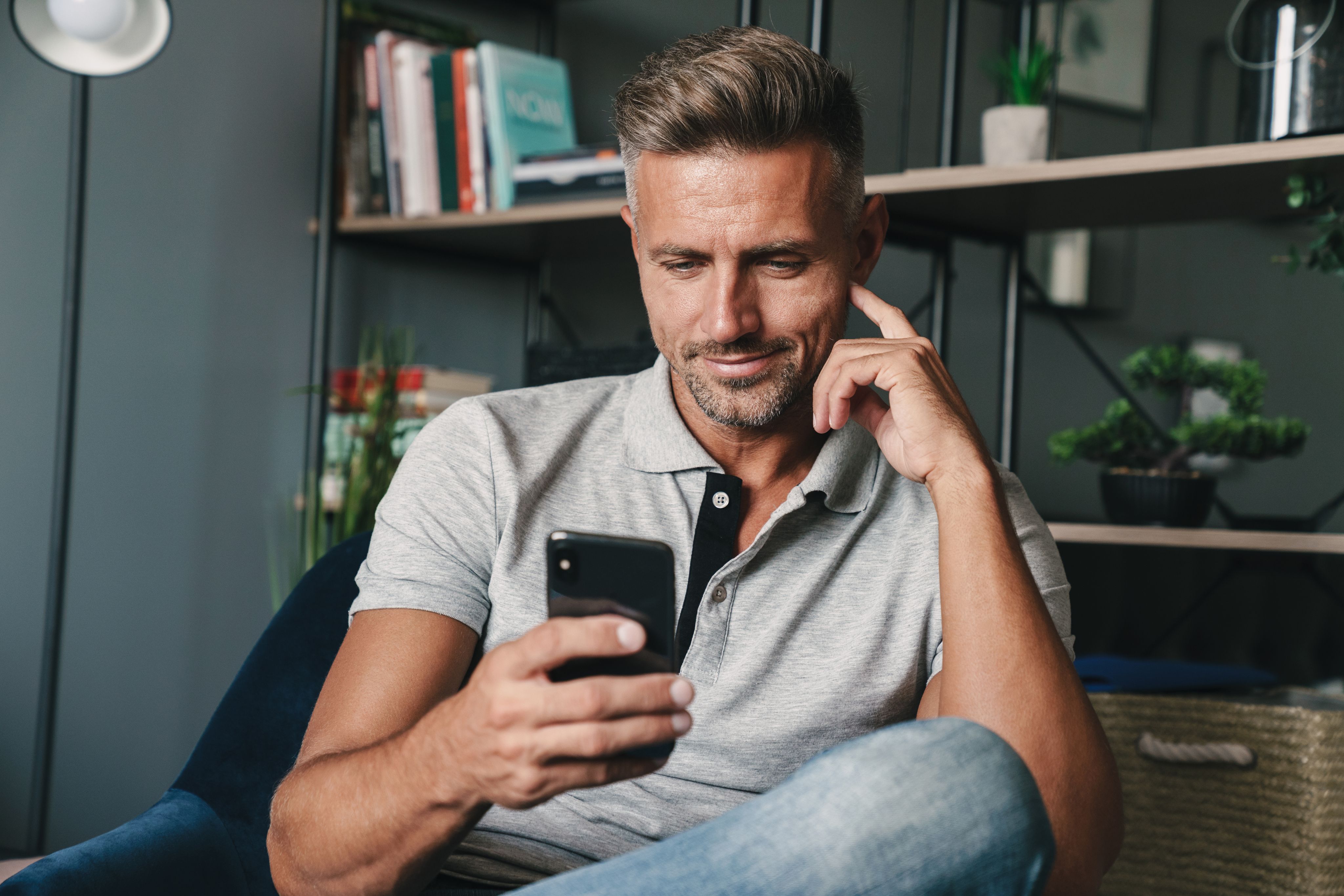 Man relaxing at home with phone — initial consultation imagery.