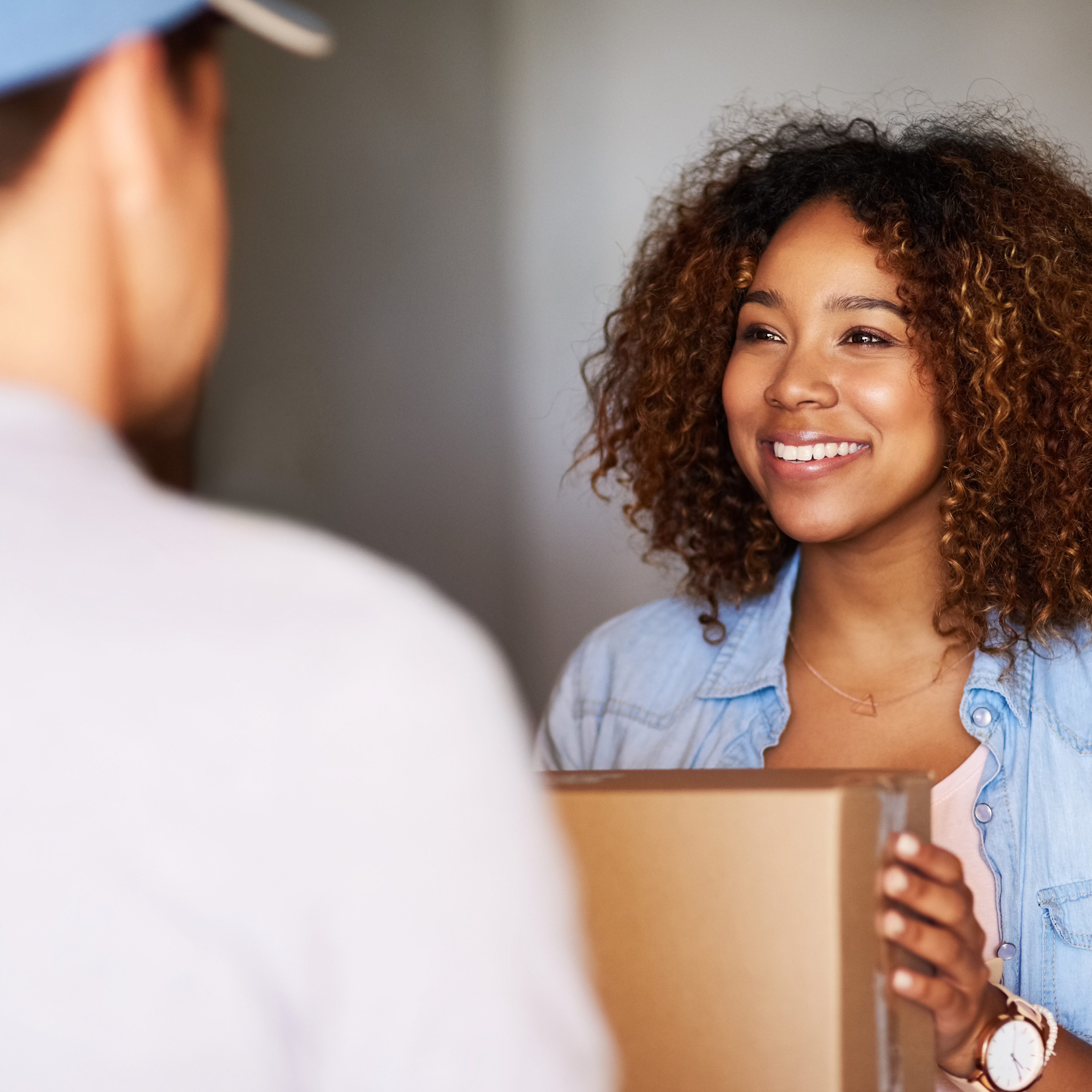 Smiling woman receiving package at door — shipment delivery imagery.
