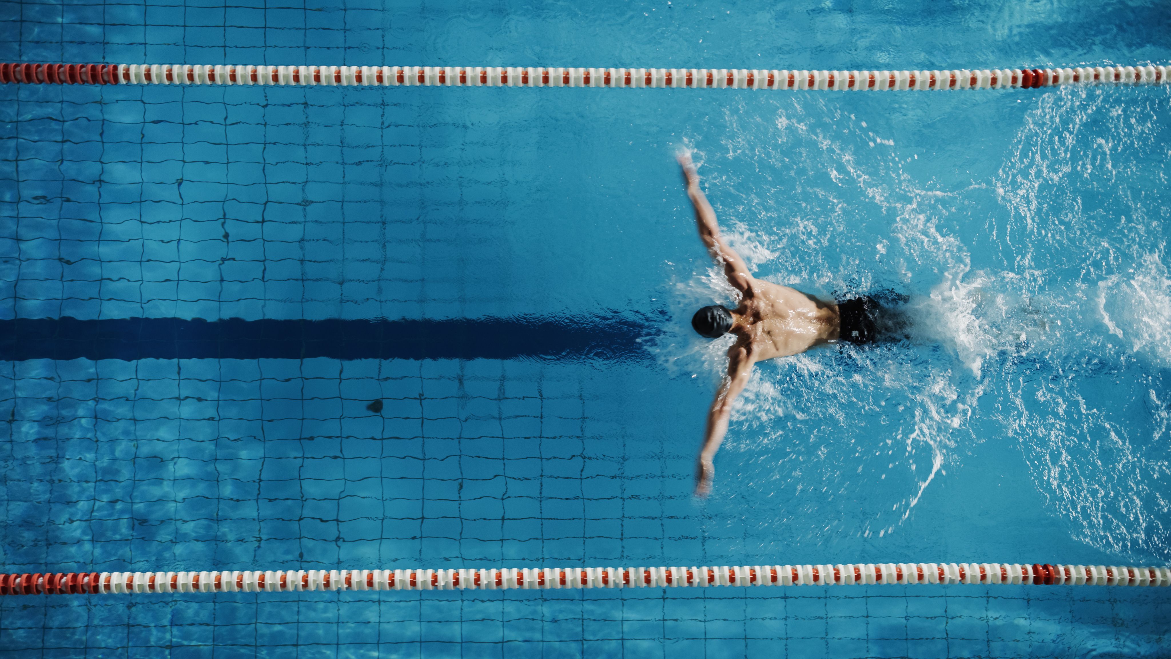 Swimmer mid-stroke in a lap pool — testimonial portrait for Jon, peptide patient.